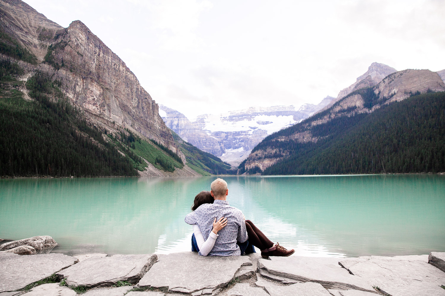 couple sitting at lake louise looking at the mountains