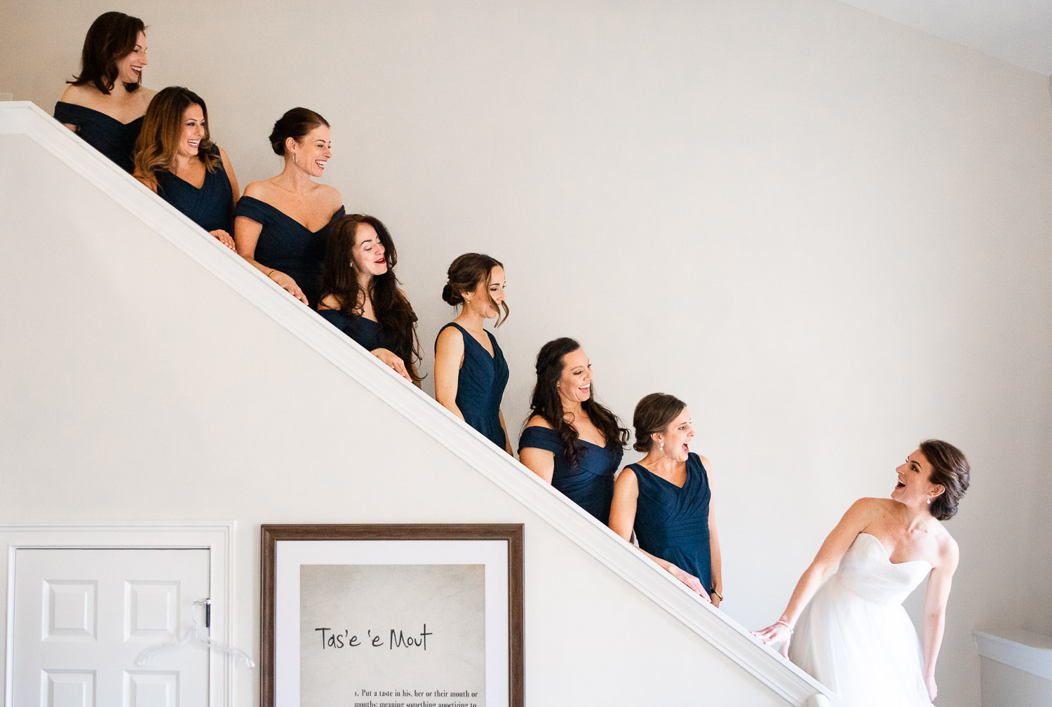 Bridesmaids wearing navy blue Azazie dresses following bride walking down stairs