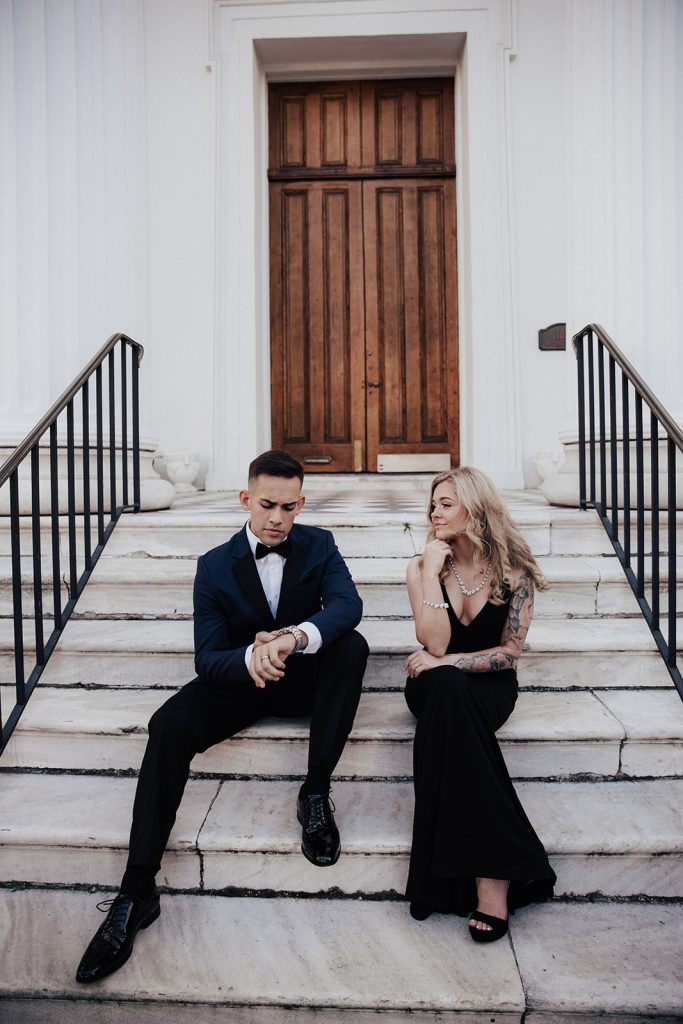 Elegant couple in blue tuxedo and black dress sitting in front of Hibernian Hall