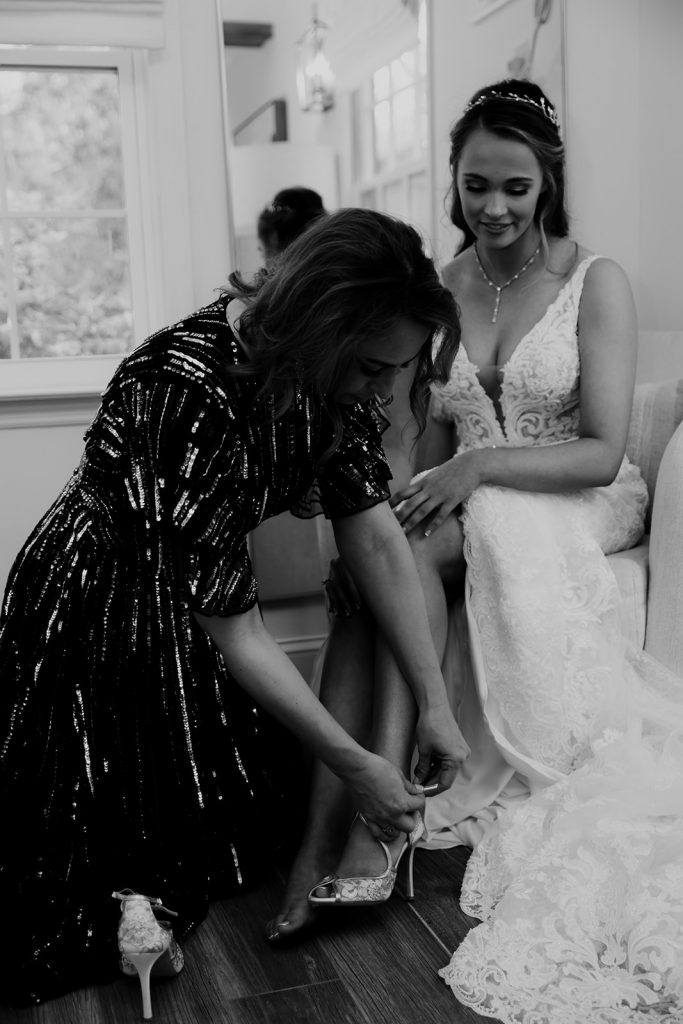 Mother helping bride into wedding shoes