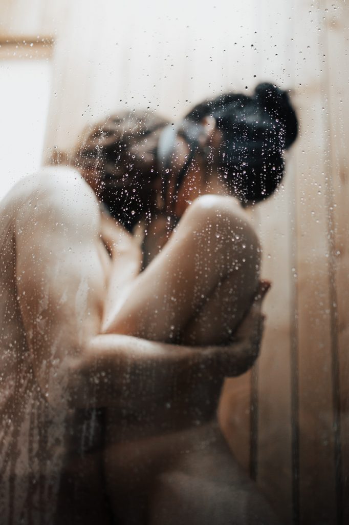 Couple kissing behind shower glass wall with water drops during Steamy Shower Engagement Session