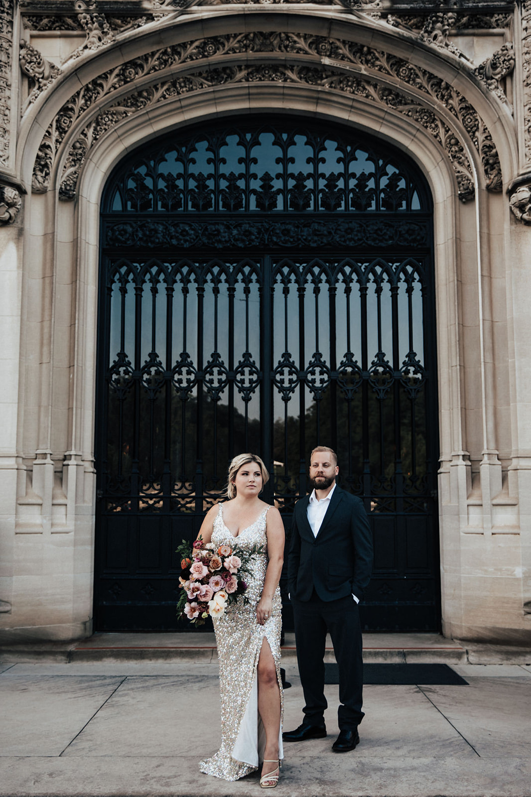 Couple in evening attire standing in front of black gate at Biltmore estate for anniversary photos