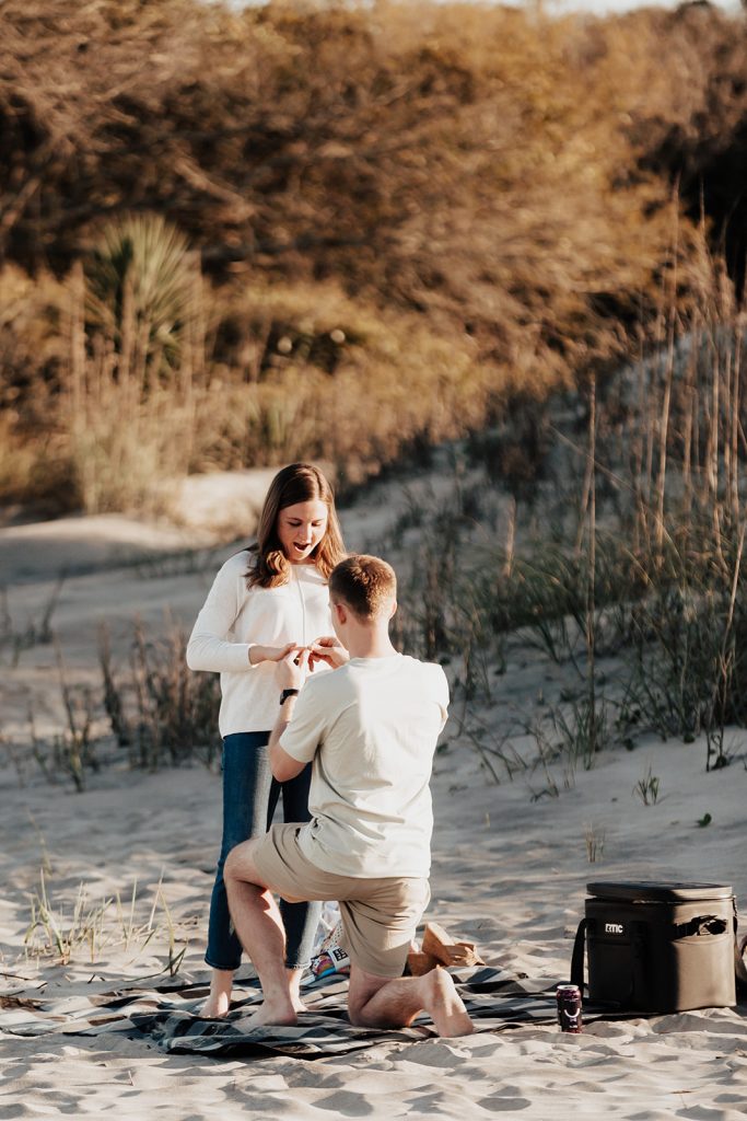 Man putting ring on finger of woman at Sunset Folly Beach Proposal