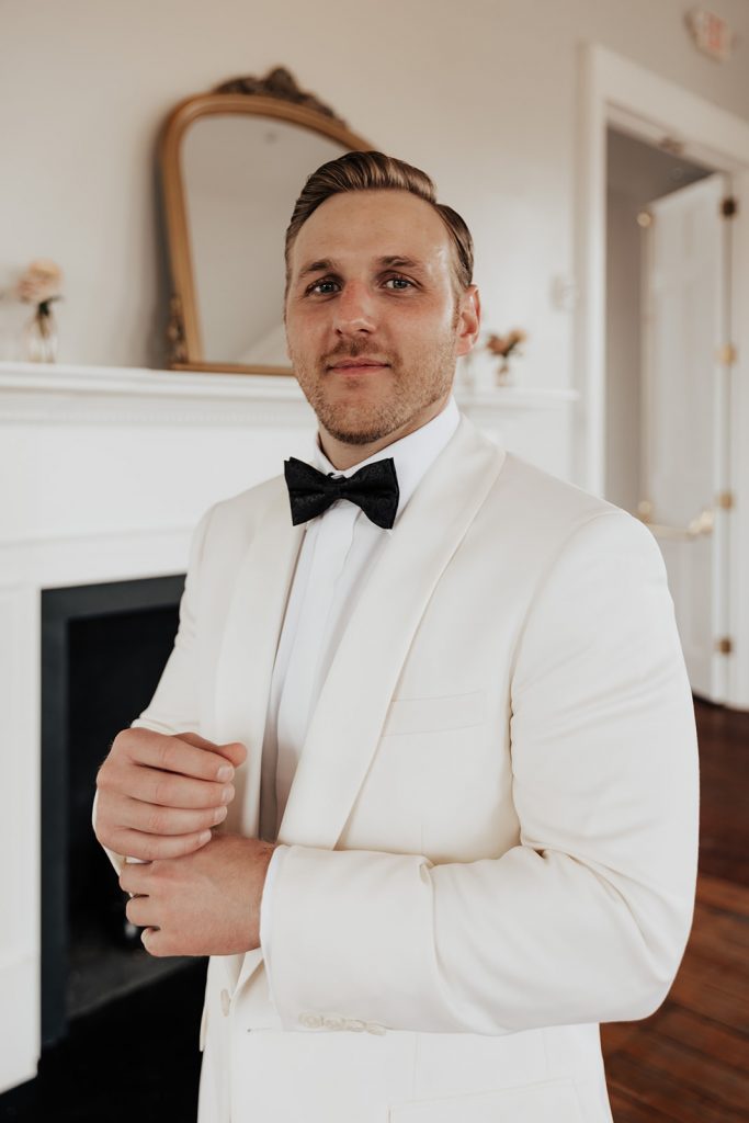 Groom in white tuxedo jacket with bow tie