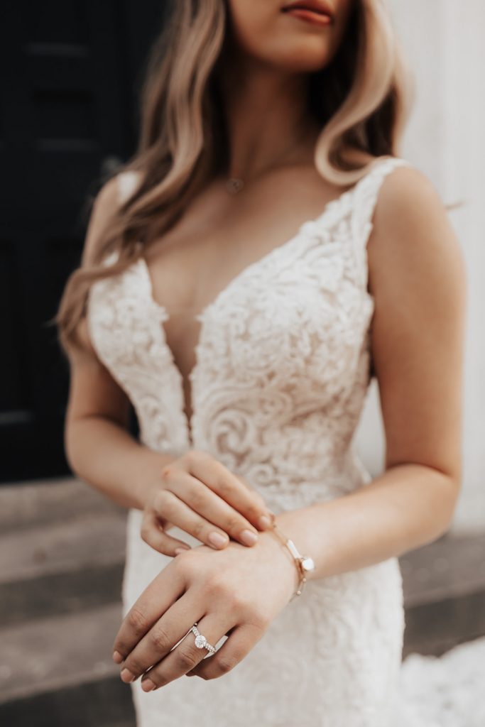 Close-up of engagement ring with bride in wedding dress in the background