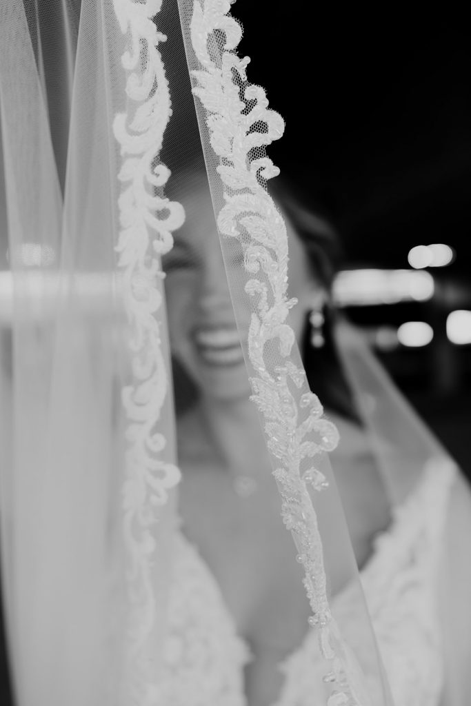 Bride smiling photographed through veil of wedding dress