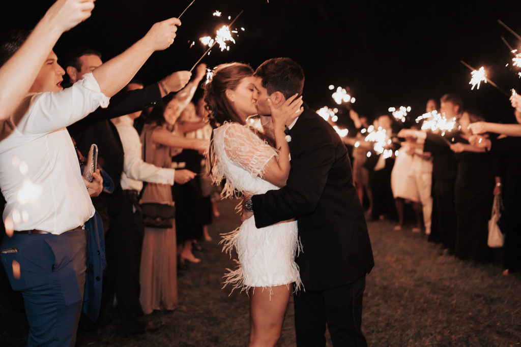 Bride and groom kissing at sparkler exit