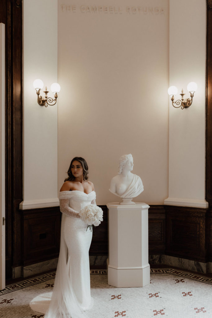 Bride standing next to statue in Gibbes Museum Charleston holding flower bouquet