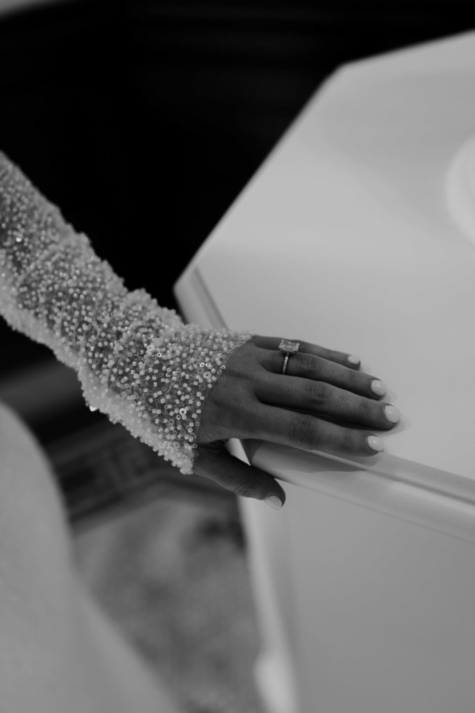 Close-up photo of long sleeve wedding dress with engagement ring 