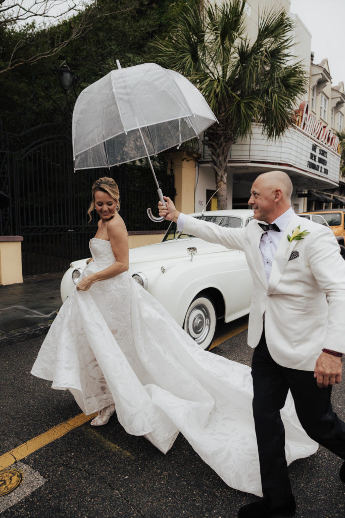 Groom holding up umbrella for bride 