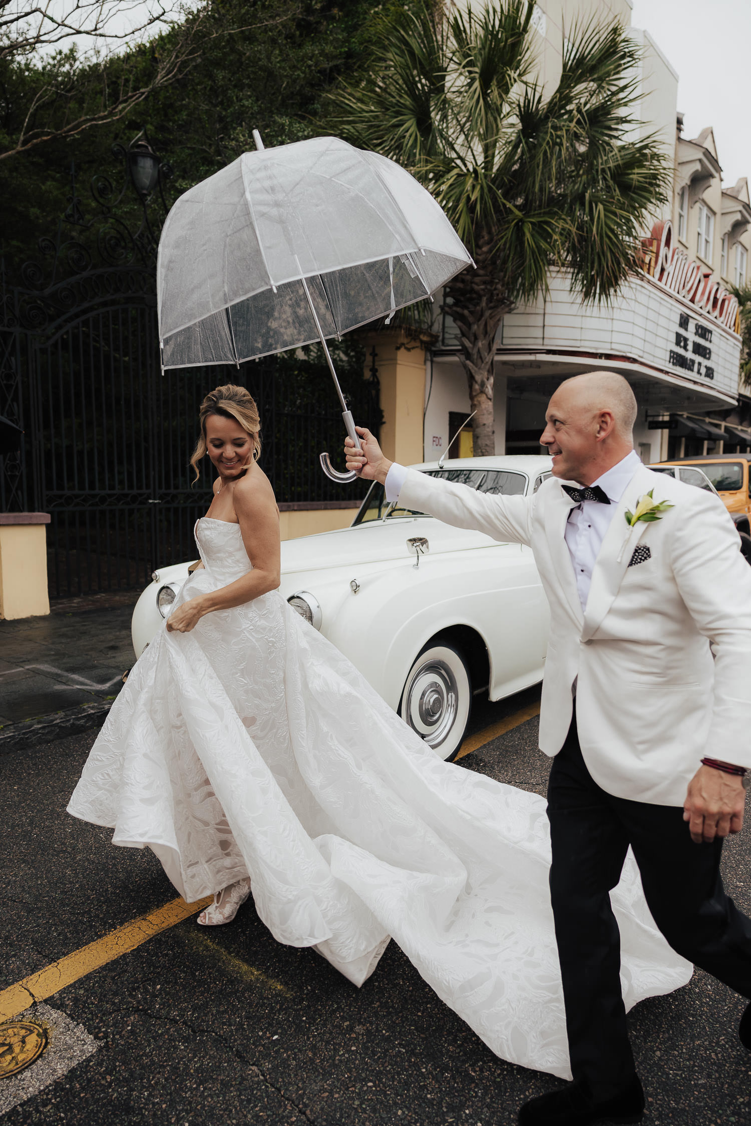 Groom holding up umbrella for bride at William Aiken House wedding