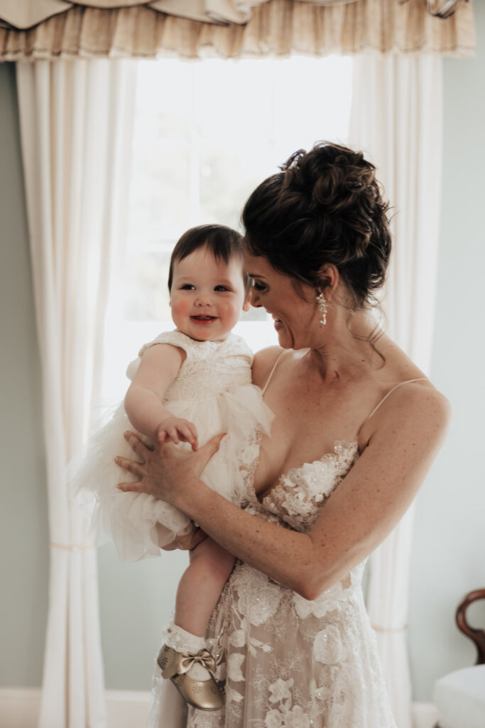 Bride holding daughter during getting ready for her wedding