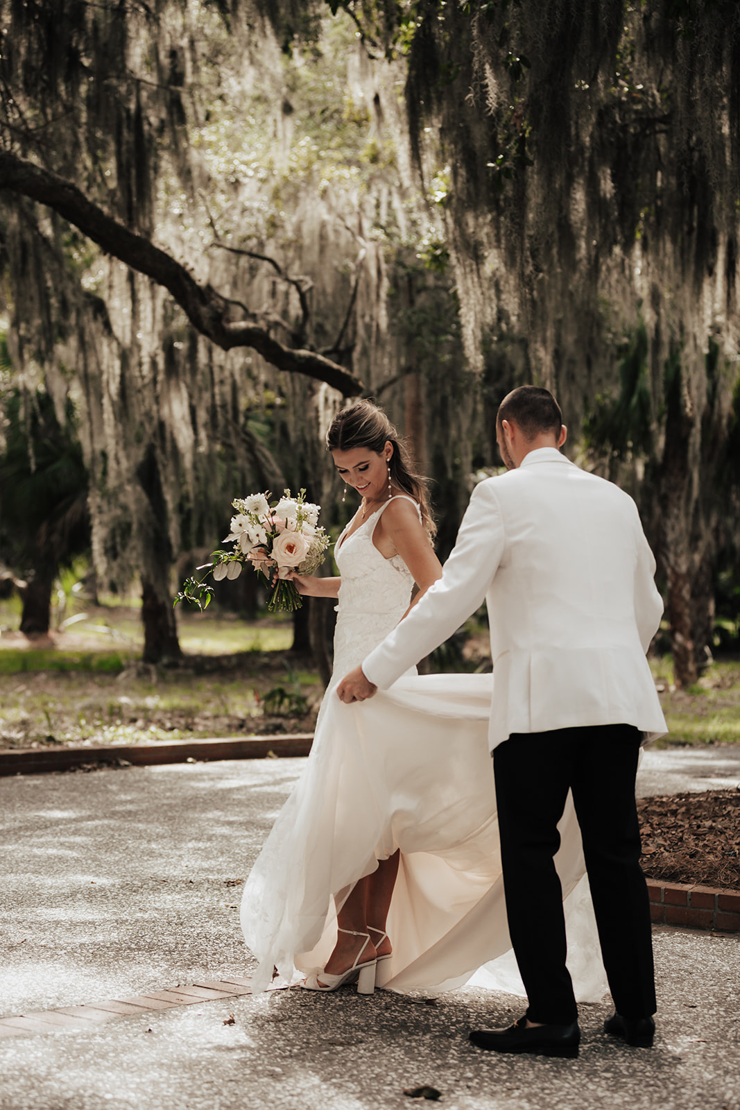 Groom flussing the dress at Daufuskie Ilsnad wedding. Couple surrounded by oak tress and spanish moss.