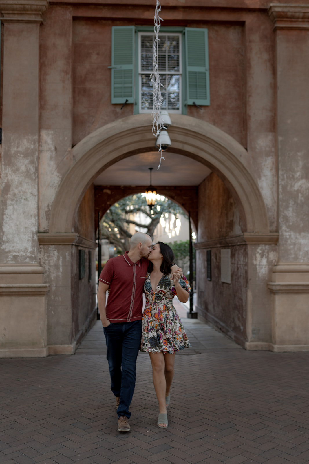 Sharing a kiss while walking through Porters Lodge at Engagement Session at the College of Charleston