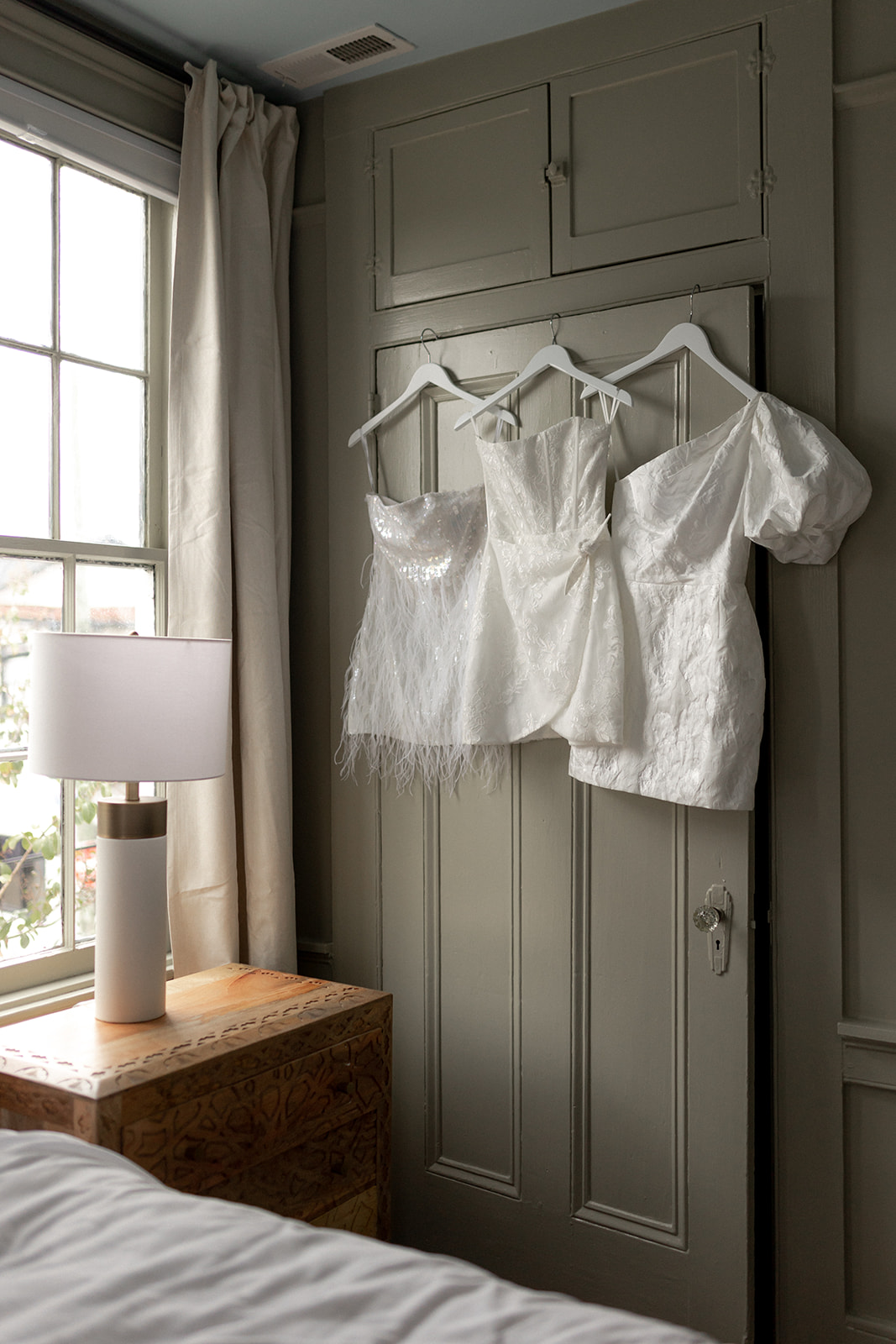 Bridal dresses hanging next to window