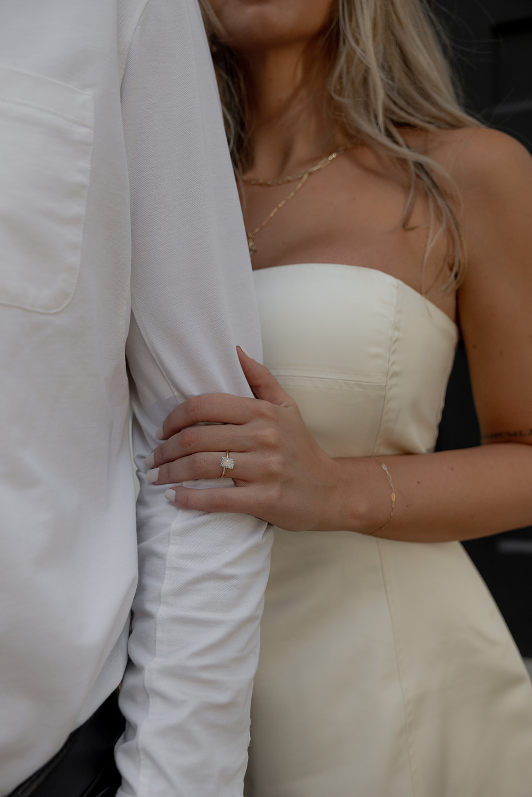 Closeup of woman in white dress holding on to arm in button down shirt for Charleston Engagement Photos