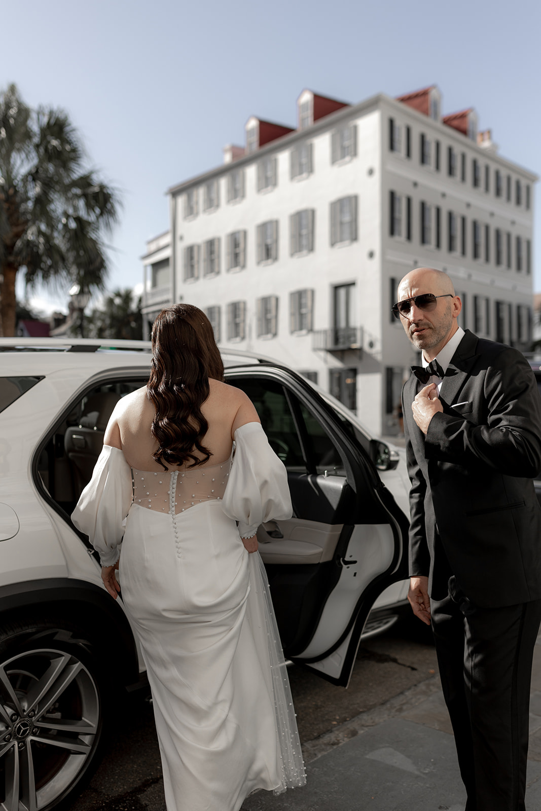 Groom holding door of Mercedes. Bride getting into car