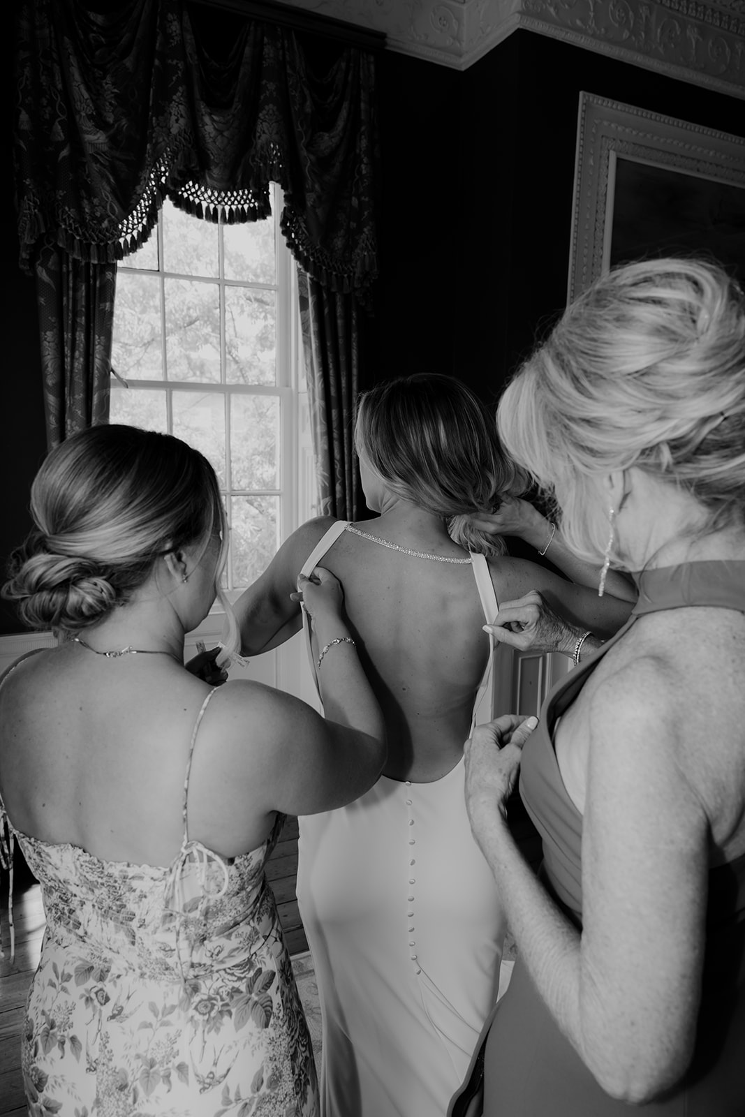 Bridesmaid and mom help bride into dress at Wedding at the William Aiken House