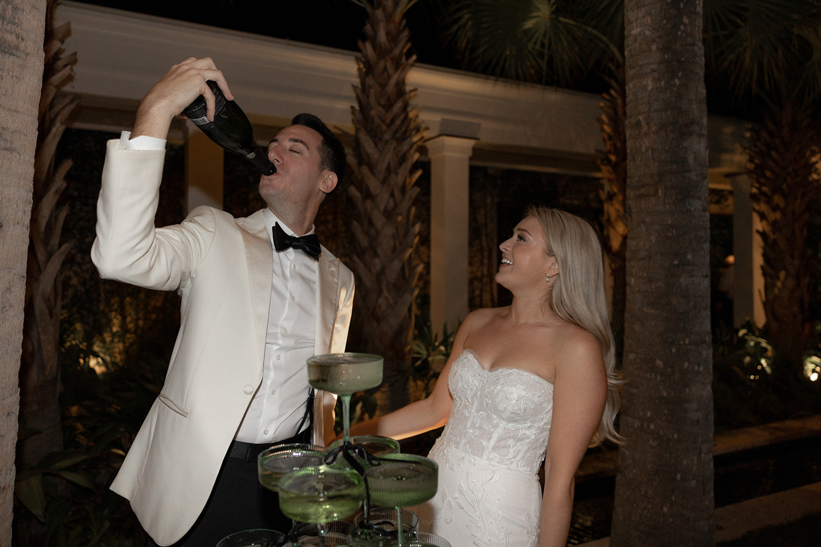 Bride and groom at champagne tower. Groom is drinking out of bottle at Wedding at Cannon Green