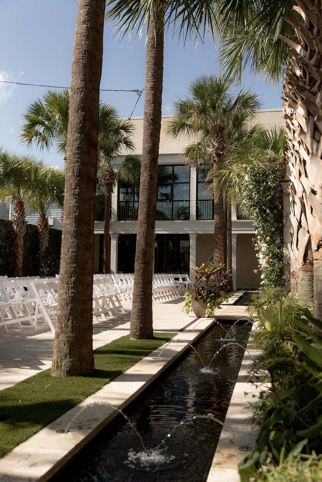 Wedding ceremony setup at Cannon Green showing palm trees and white chairs