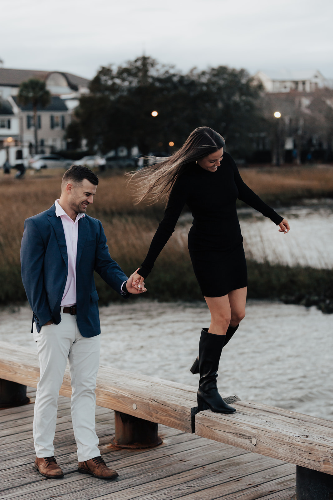 Playful balancing at public pier in Charleston during engagement photo session