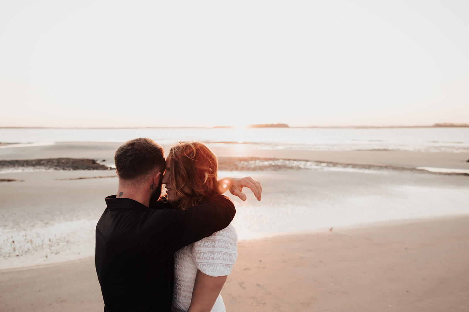 Couple head to head looking at the ocean at Folly Beach Engagement Session. Sunset at the horizon.