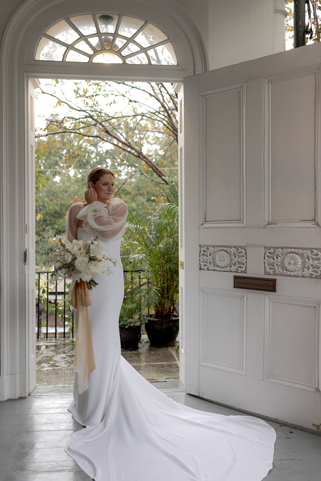 Bridal portrait taken at Wedding at Gov. Thomas Bennett House. Bride standing in tall doorway with bouquet.