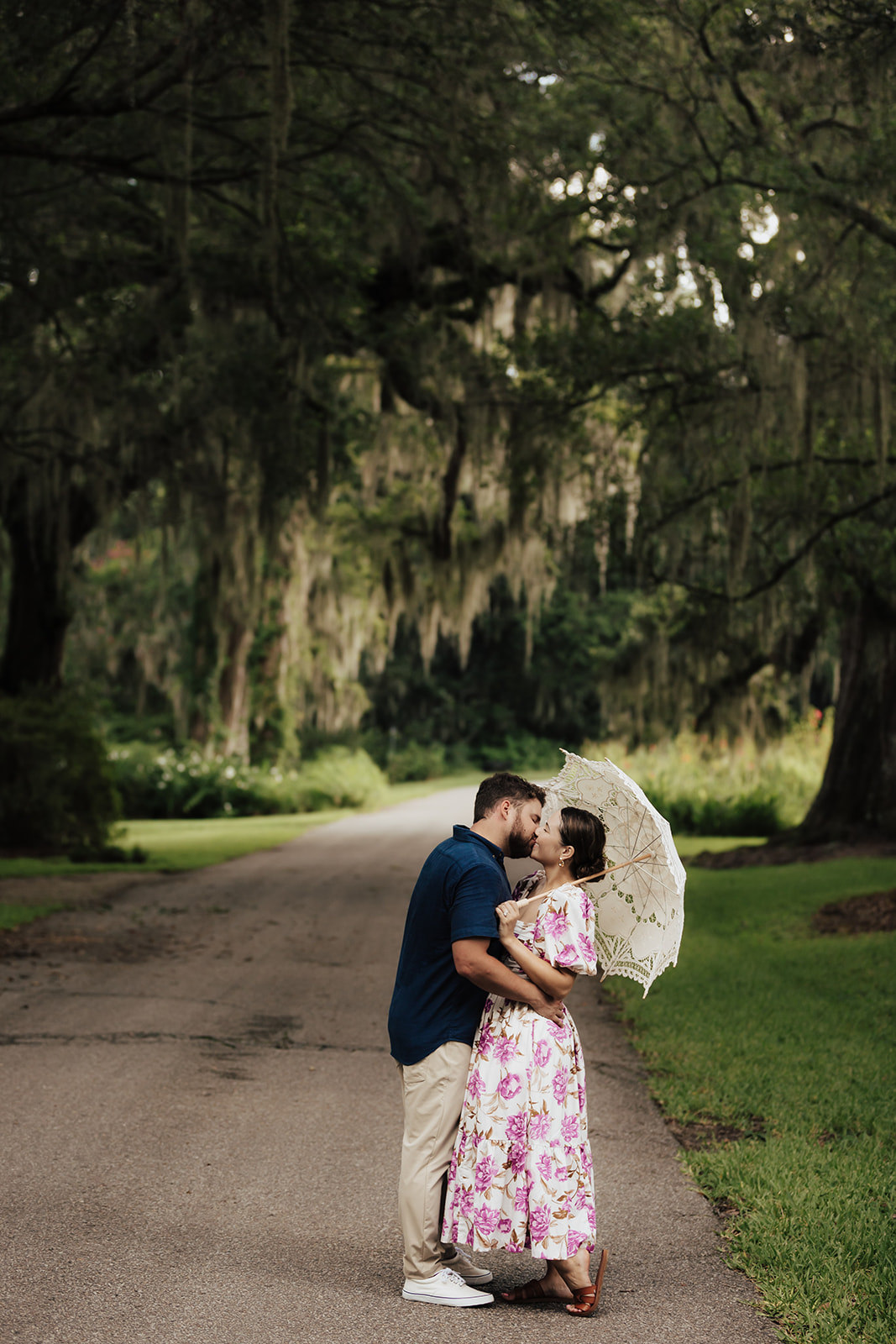 Couple kissing on street lined with massive oaks trees after magnolia plantation proposal