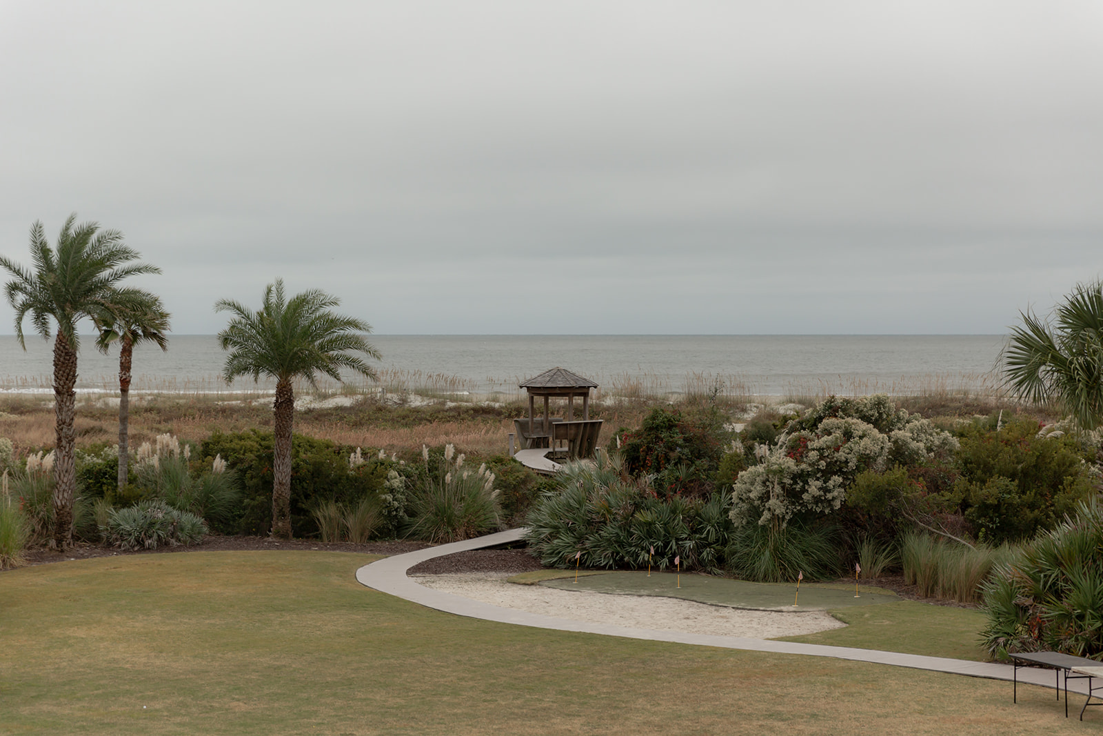 Gettin gready location at the beach. View from Isle of Palms beach house. Ocean in the background. Palms and a wooden Pavilion at the end of a path way.