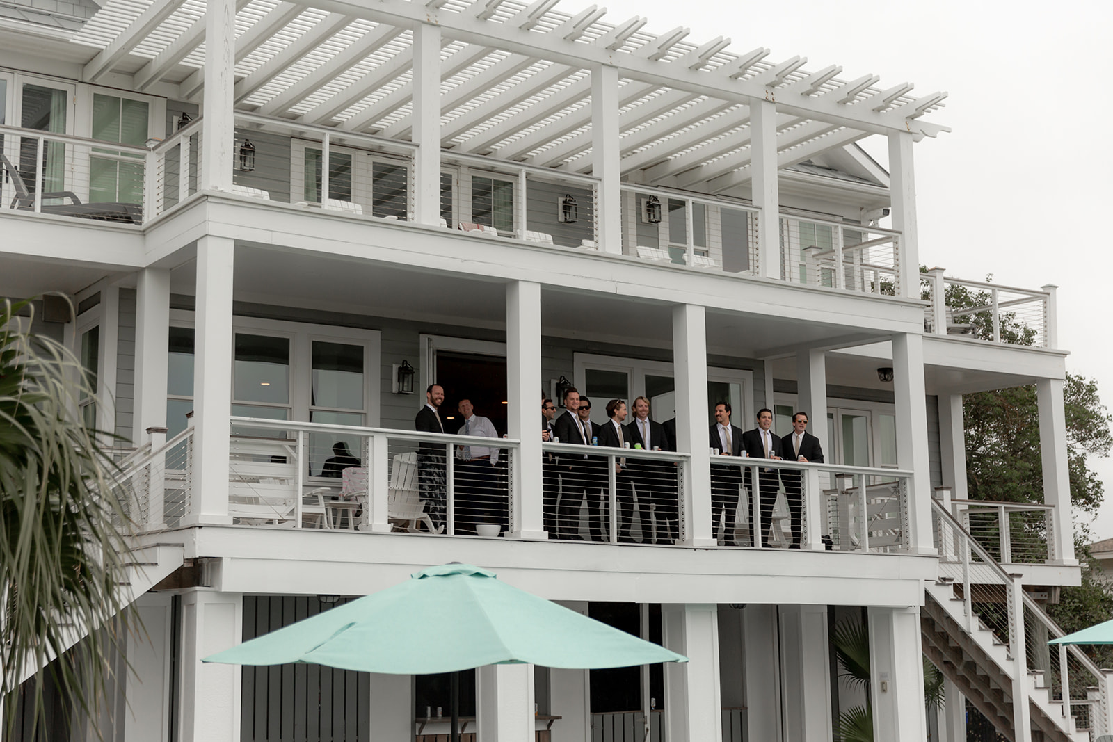 Groomsmen enjyoing the getting ready process on a porch of a white beach house before heading to a Wedding at Gov. Thomas Bennett House
