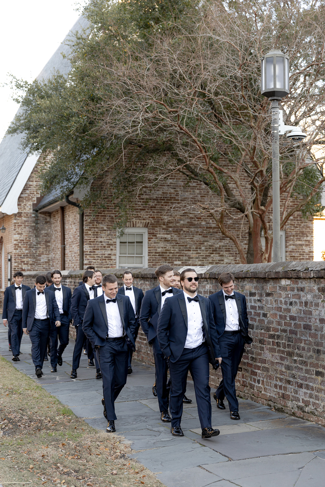 Groom and groomsmen walking along the sidewalk to enter the church