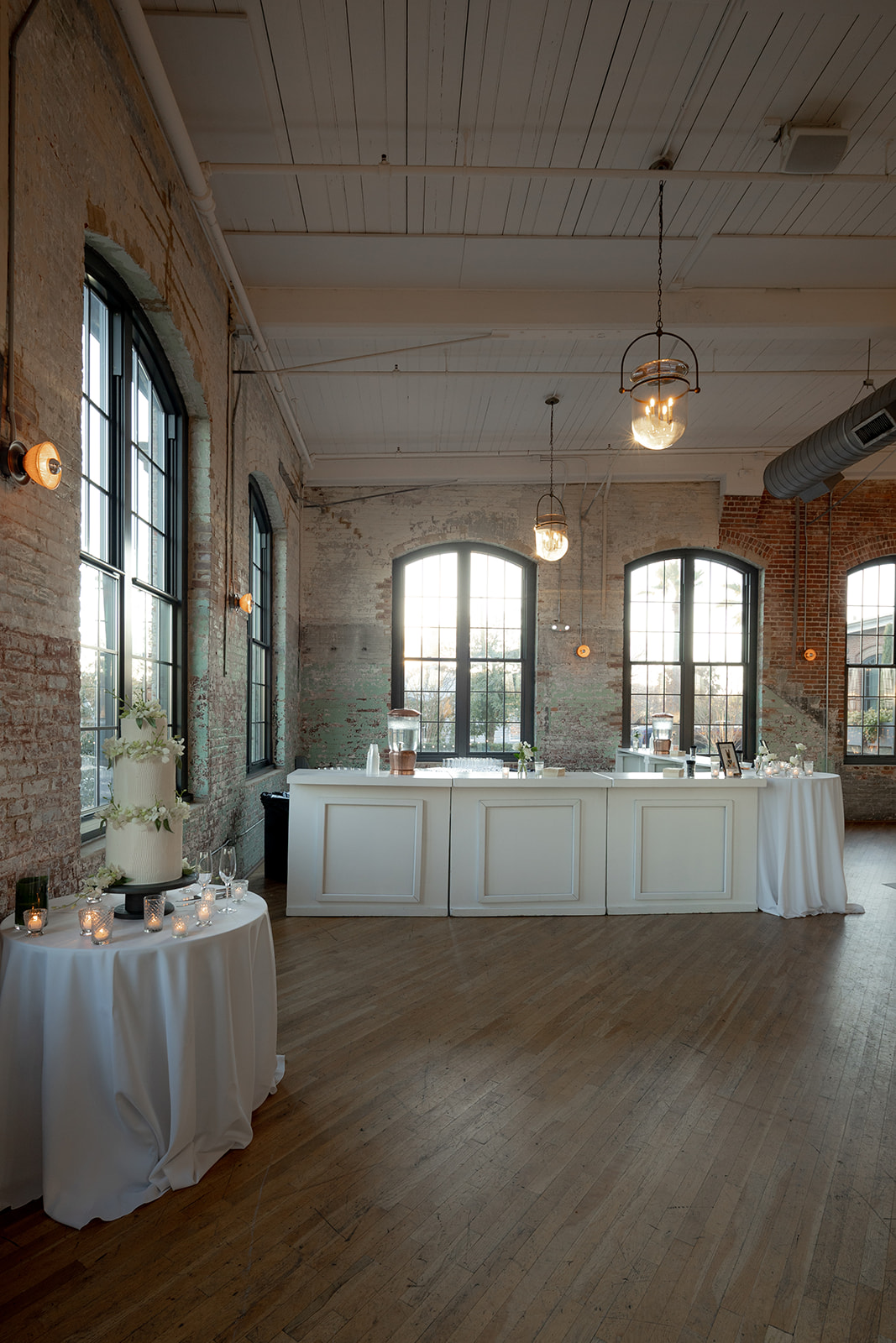 Bar and wedding cake setup at Cedar Room wedding. Brick wall and tall windows in the background
