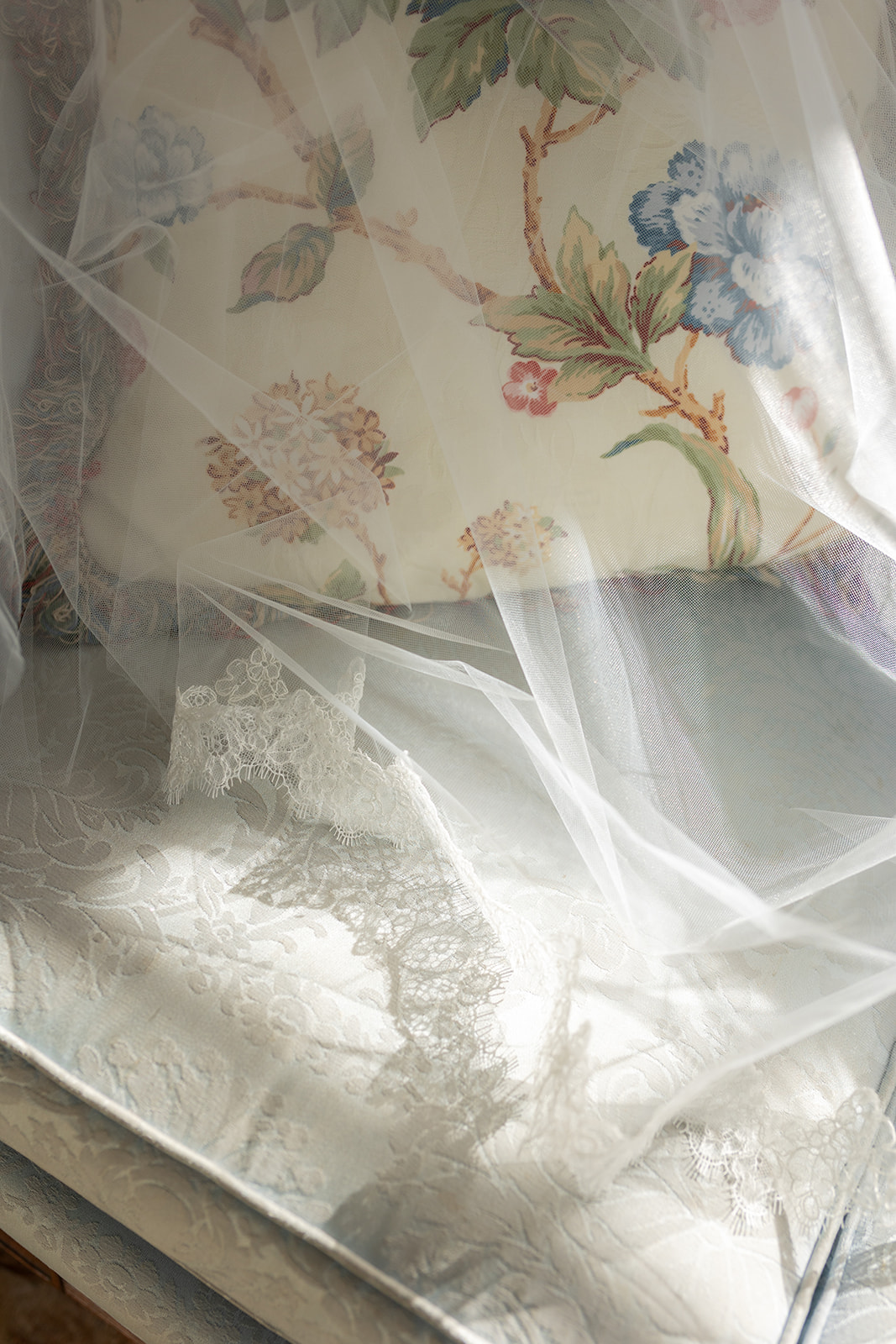 Wedding veil on sofa with flower pillow photographed.