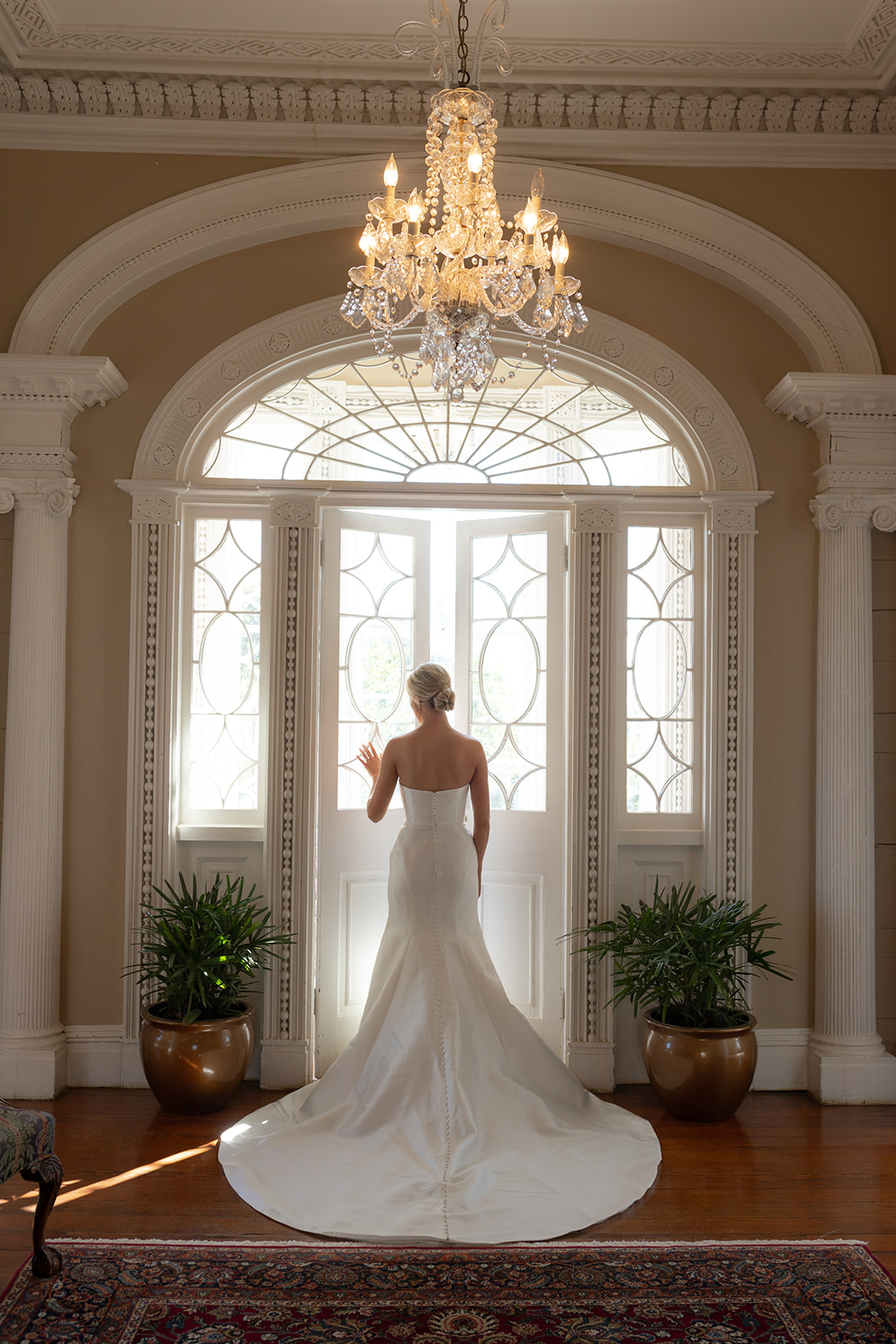Bride standing in front of ornamental door and window at gov. thomas Bennett House for photo session to showcase wedding dress in Charleston