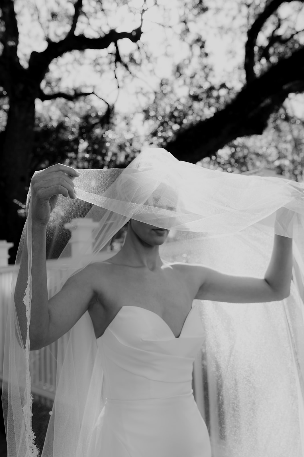 Black and white photo of bride lifting wedding veil during wedding dress photo session in Charleston
