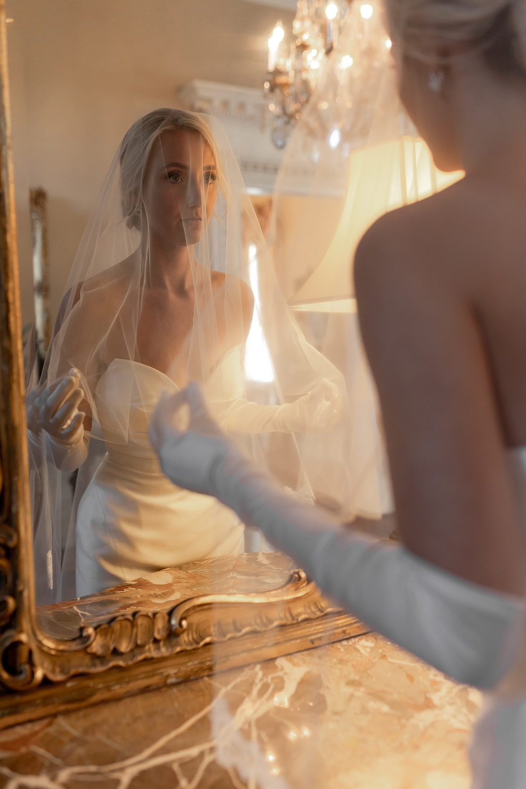 Golden framed mirror showing woman in wedding dress. Photographed over brides shoulder.