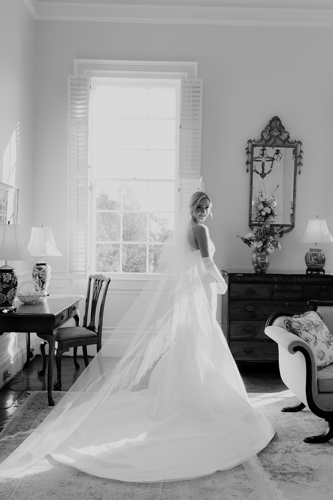 Black and white photo of bride in wedding dress standing in historic home in Charleston