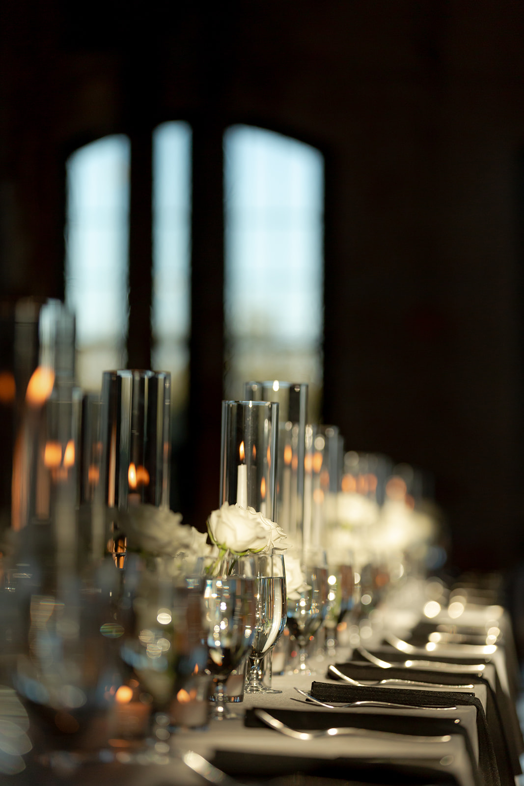 Wedding reception table setup with tall candle glasses and white roses at Cedar Room Charleston