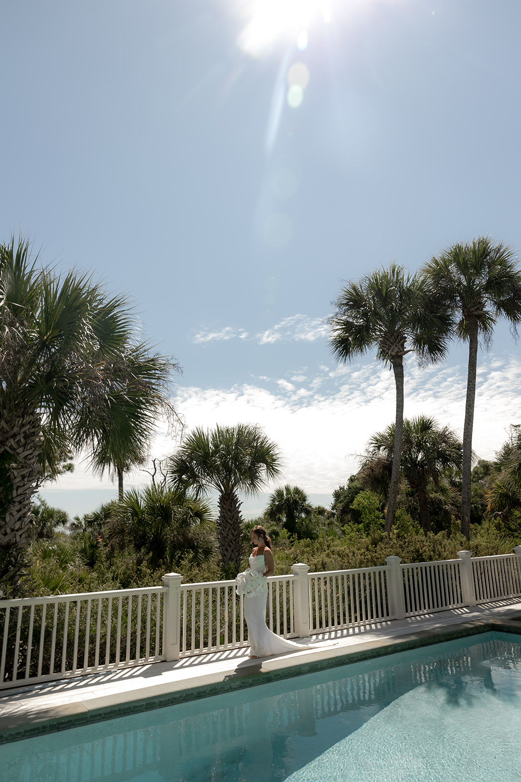 Bride walking along pool with palmetto trees in background at getting ready location on Kiawah Island