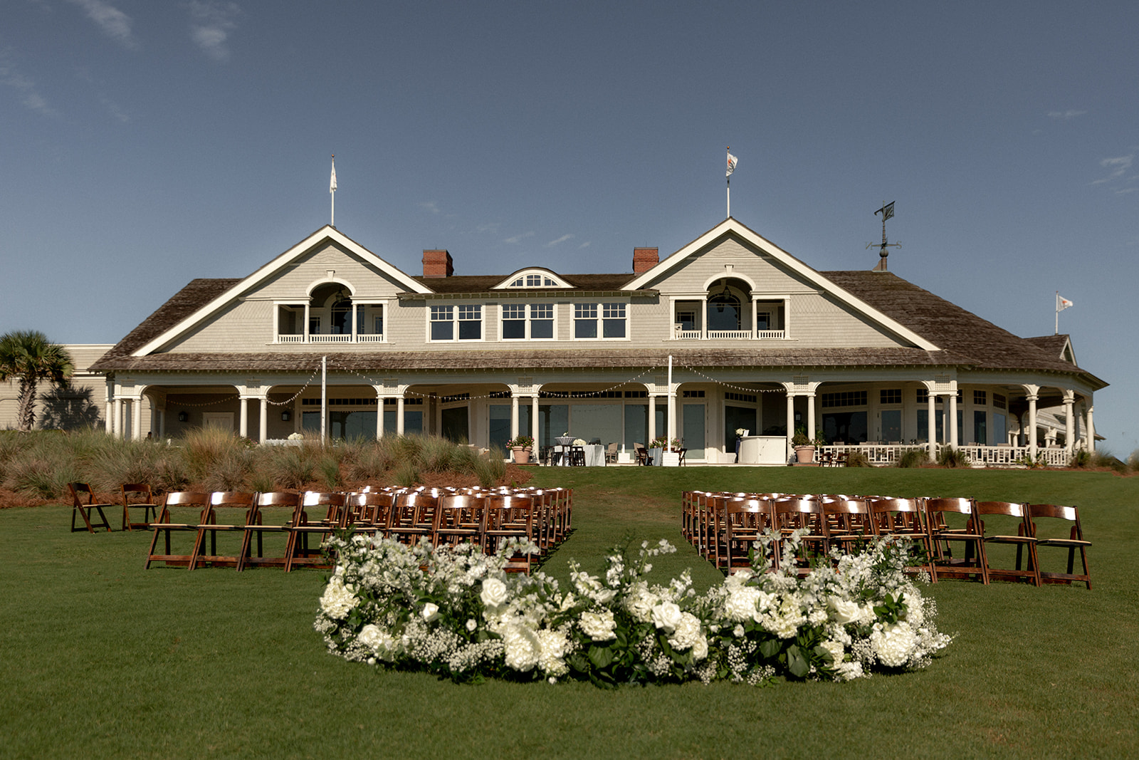 Kiawah Ocean Course wedding ceremony setup. Flowers and chairs with Kiawah club house in the background