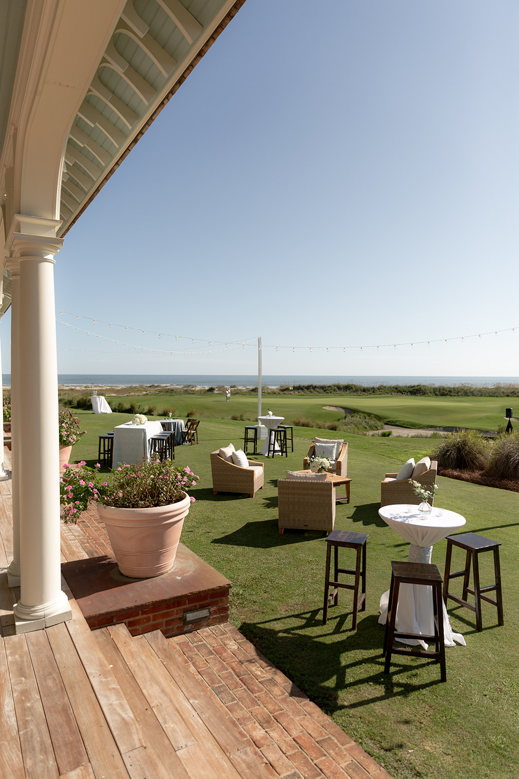 Outdoor cocktail hour setup with high tables and lounge seating for Kiawah Ocean Course wedding