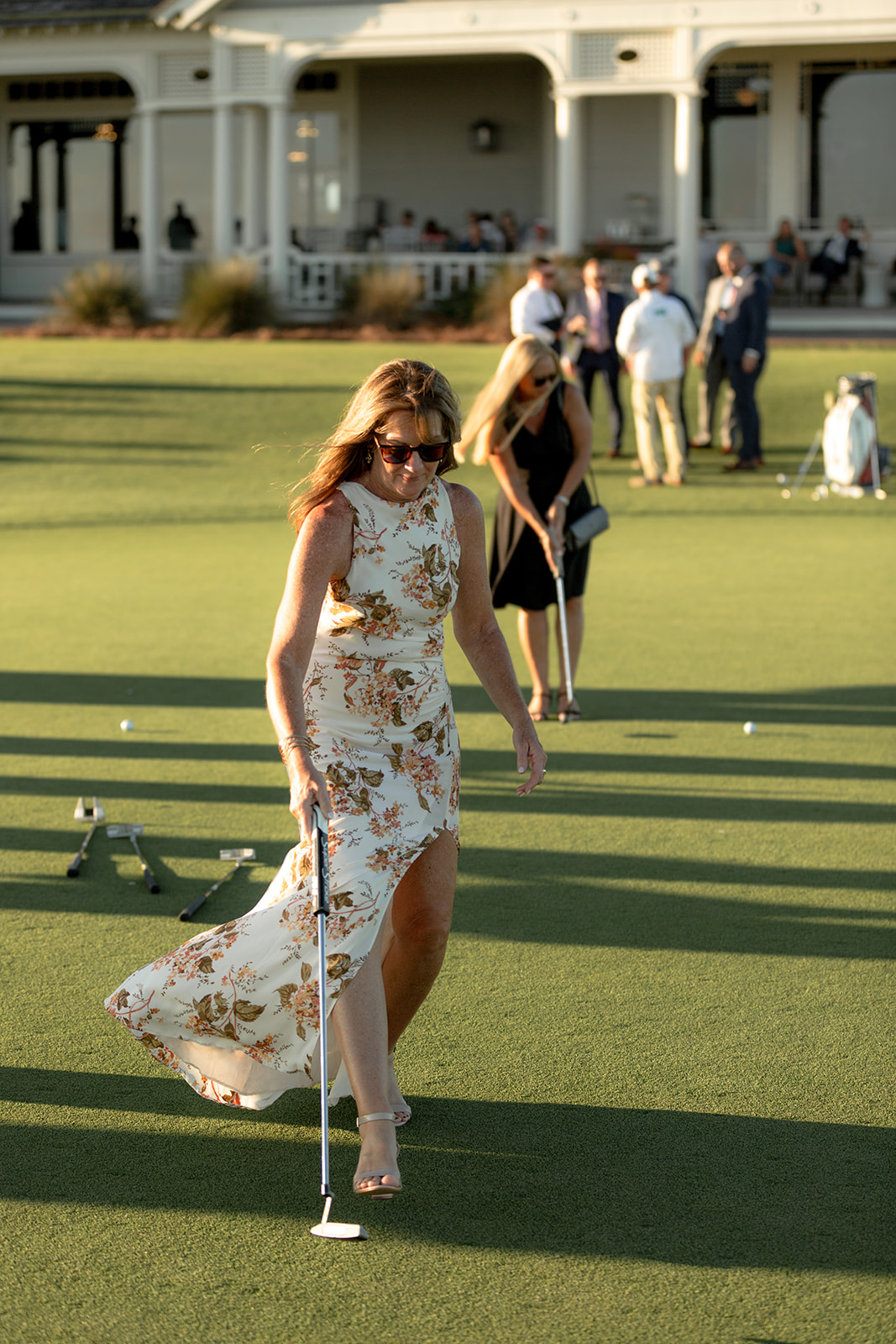 Wedding guest in flower dress participating in putting contest during cocktail hour at Kiawah Ocean Course wedding
