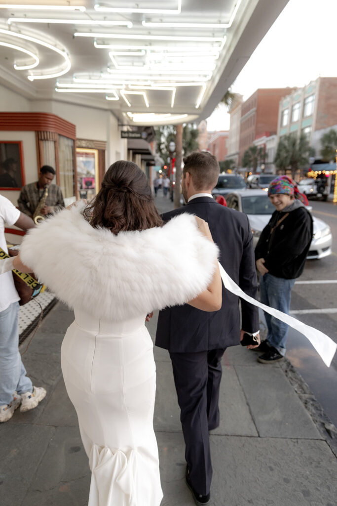 Bride and groom walking in front of American Theatre in Charleston