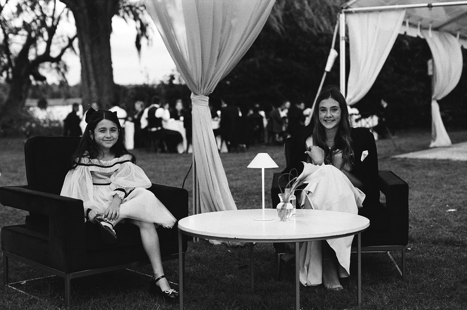 Black and white film photo of young wedding guests sitting at table