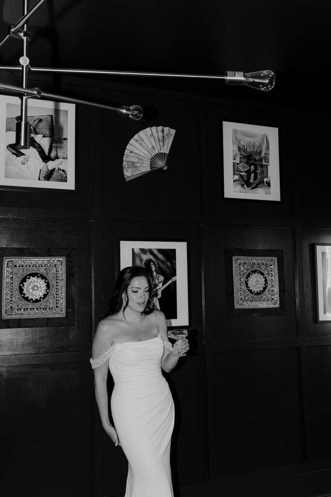 Charleston Elopement bride standing in front of photo wall with glass in her hand