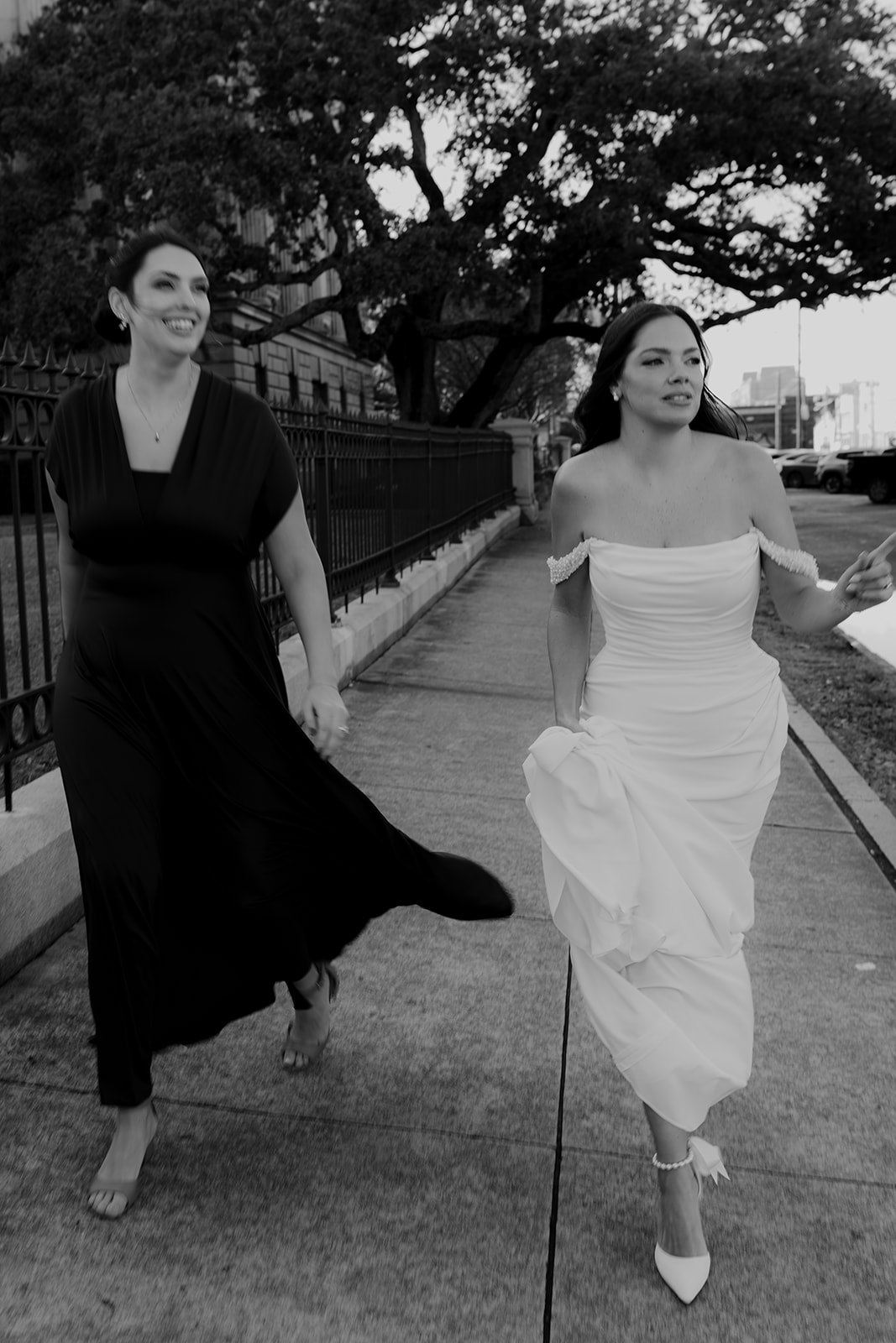 Black and white photo of bride and friend walking an sidewalk to Charleston Elopement ceremony