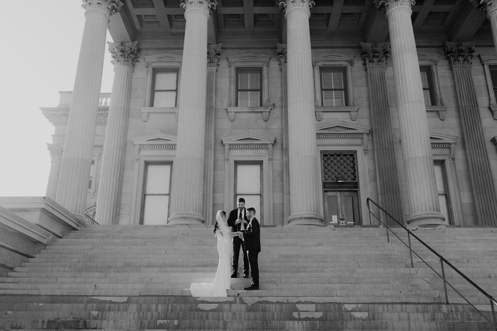 Couple and officiant standing in fron tof US Custom House in Charleston during ceremony