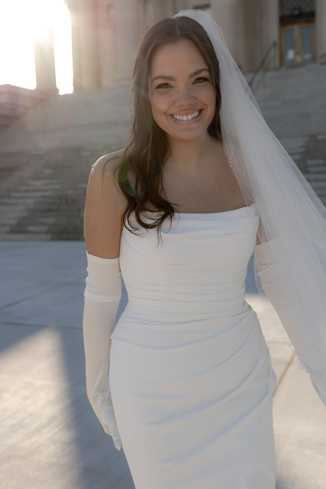 Bride smiling into camera and sun beams coming from behind