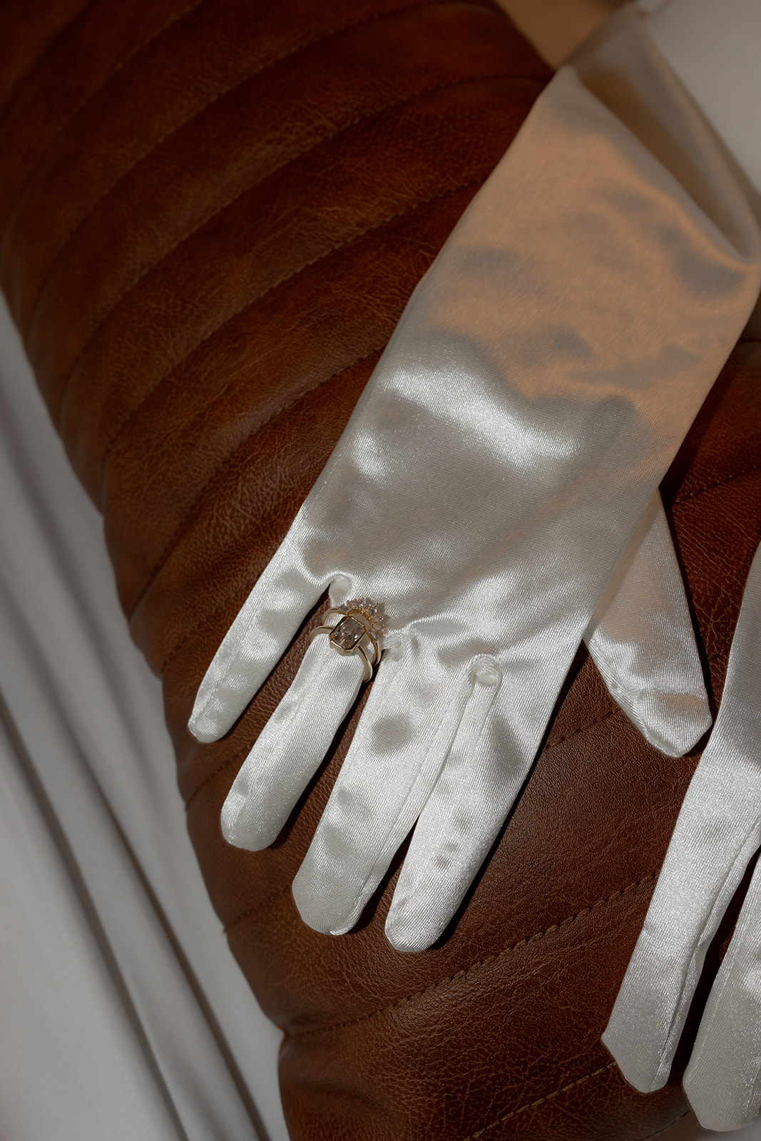 White gloves with ring on brown leather couch