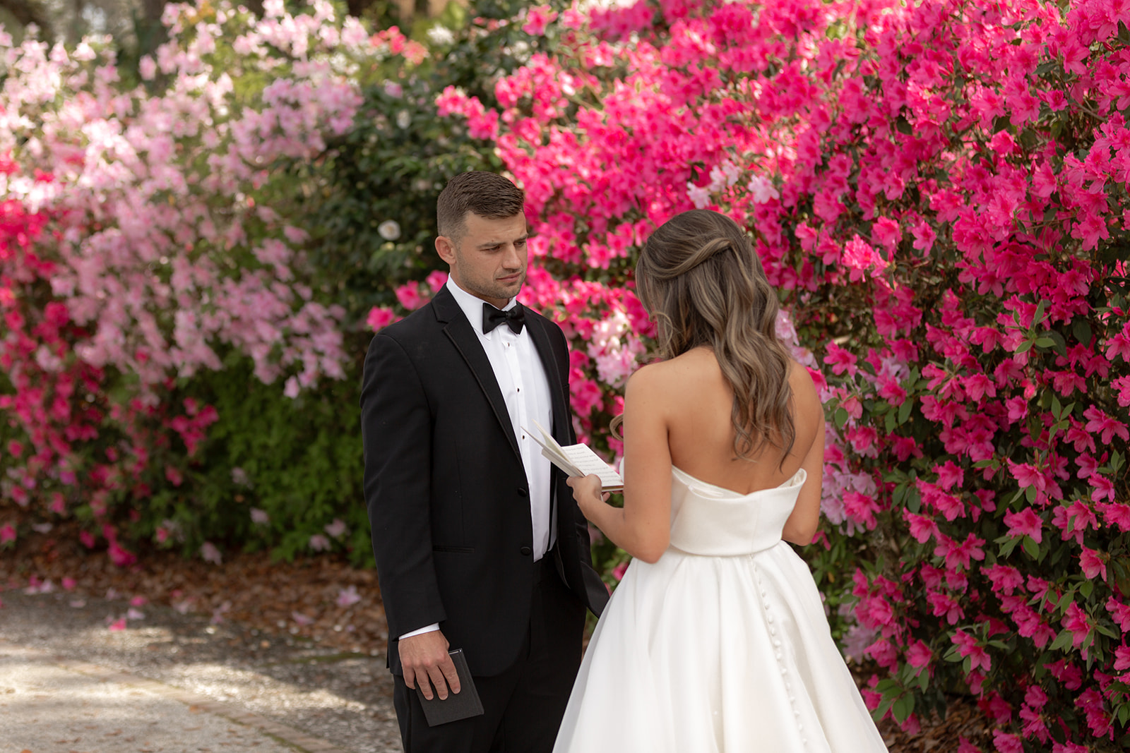 Bride and groom reading vows in fron tof red azaleas at Magnolia Plantation and Garden.